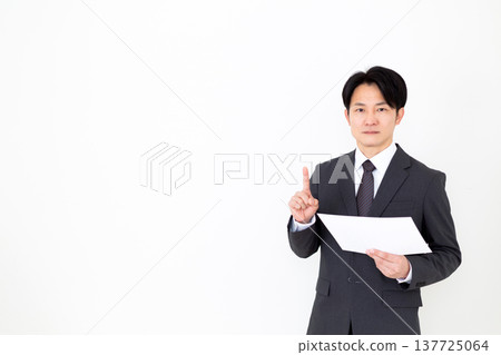 一位身穿西裝的中年商人一邊看著圖表，一邊舉起食指。 137725064