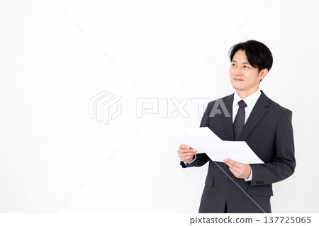 A middle-aged businessman in a suit looking at a graph. A middle-aged businessman in a suit looking at a graph. 137725065