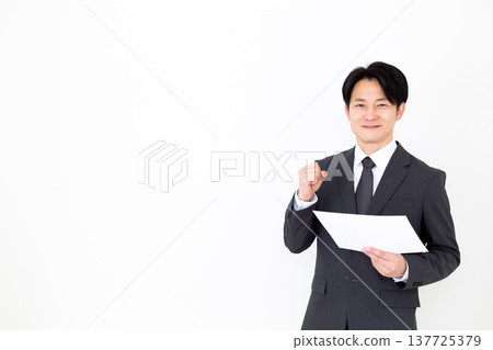 一位身穿西裝的中年商人看著圖表，做出了一個得意的手勢。 137725379