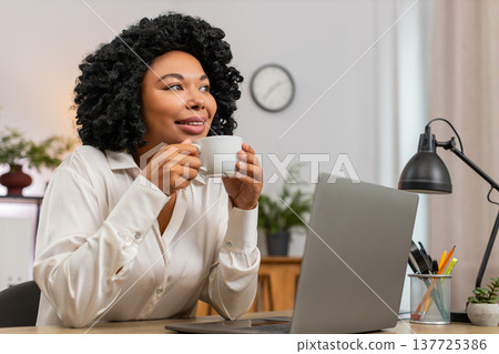 African American businesswoman drinks coffee thinking near window resting from work for inspiration African American businesswoman drinks coffee thinking near window resting from work for inspiration 137725386