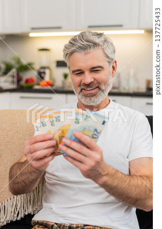 Middle-aged man counts money cash euros smiles at big plans purchase salary bonus savings investment Middle-aged man counts money cash euros smiles at big plans purchase salary bonus savings investment 137725433