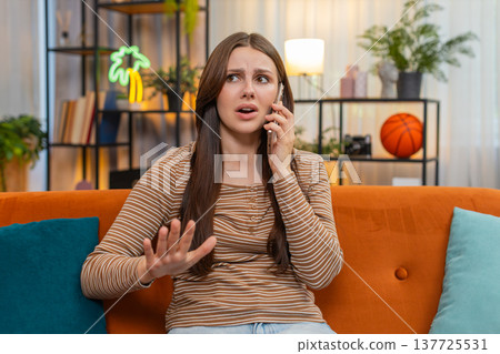 Young woman argues on smartphone frowns sharp hand moves raises voice and speaks fast in tense call 137725531