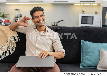 Indian man saves files makes backup closes laptop smiles relief and leans back after finishing work Indian man saves files makes backup closes laptop smiles relief and leans back after finishing work 137725713