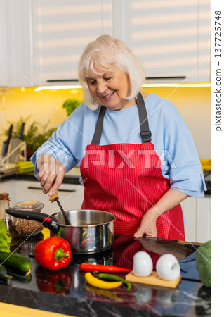 Senior old woman cooking homemade soup in kitchen tasting seasoning for healthy diet family dinner Senior old woman cooking homemade soup in kitchen tasting seasoning for healthy diet family dinner 137725748