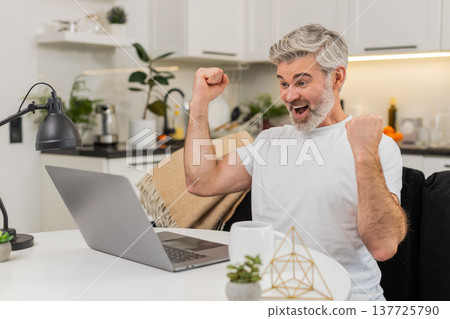 Middle-aged man celebrates discount and promo code success on laptop cheers for jackpot lottery win Middle-aged man celebrates discount and promo code success on laptop cheers for jackpot lottery win 137725790