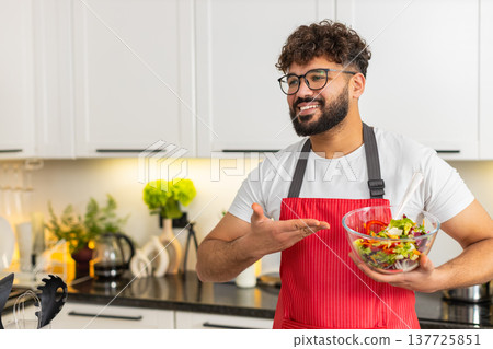 Arabian young man filming vlog in kitchen holding salad bowl teaching keto diet healthy eating guide Arabian young man filming vlog in kitchen holding salad bowl teaching keto diet healthy eating guide 137725851