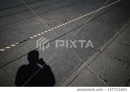 A rope marking a restricted area and the shadow of a person. 137725863