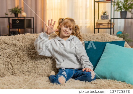 Young teenager girl waving hand with cheerful expression saying hello or goodbye indoors at home 137725878