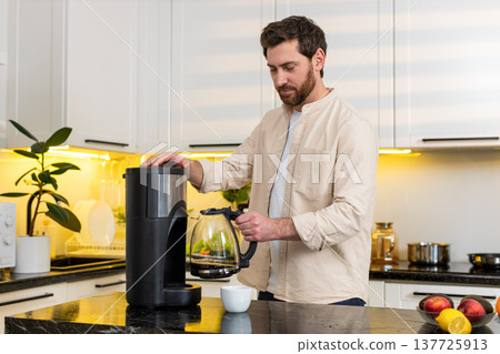 Middle-aged man enjoying fresh coffee aroma in home kitchen before breakfast morning with calm smile 137725913