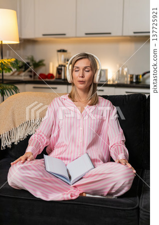 Adult woman in headphones meditation playlist breathes calm eyes closed then writes idea in notebook Adult woman in headphones meditation playlist breathes calm eyes closed then writes idea in notebook 137725921