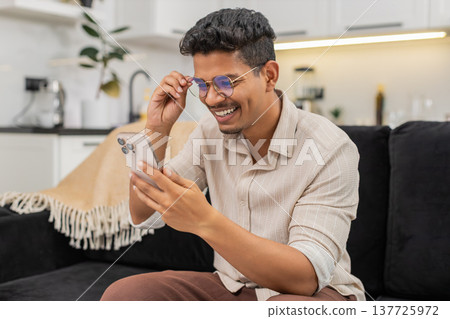 Indian man puts on glasses to read long small text on smartphone sharp vision returns continues chat Indian man puts on glasses to read long small text on smartphone sharp vision returns continues chat 137725972