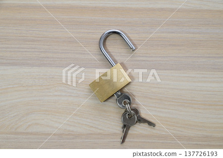 Unlocked padlock and key on a wood grain background Unlocked padlock and key on a wood grain background 137726193