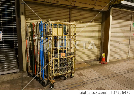 A shopping cart and shutters left in the shopping street after closing time. A shopping cart and shutters left in the shopping street after closing time. 137726422