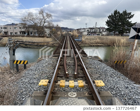 The railway tracks continue on and on, crossing the river. 137726467