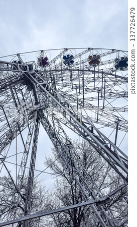 A Ferris wheel in the rays of the setting sun in a winter city park. A Ferris wheel in the rays of the setting sun in a winter city park. 137726479