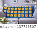 A knitted throw with a floral pattern on a sofa in a bright living room. AI 137726507