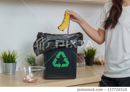 Waste Management. Woman discarding banana peel into recycling bin. Waste Management. Woman discarding banana peel into recycling bin. 137726528