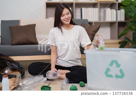 Sustainability. Young woman recycling plastic bottles at home for environmental responsibility. Sustainability. Young woman recycling plastic bottles at home for environmental responsibility. 137726536