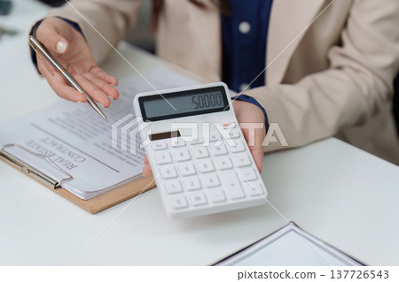 Financial Planning in Real Estate. Professional discussing contract terms with calculator. Financial Planning in Real Estate. Professional discussing contract terms with calculator. 137726543