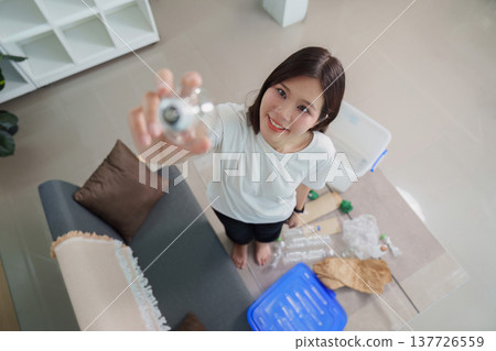 Sustainability. Young woman recycling plastic bottles at home. Sustainability. Young woman recycling plastic bottles at home. 137726559