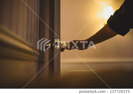 A hand opens the door to a hotel room. 137726575