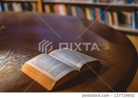 一張圓桌上擺放著古籍，背景是書架。 137726602