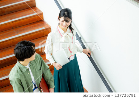 A man and a woman talking on the stairs at a company 137726791