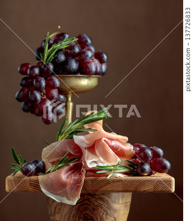 Prosciutto with grapes and rosemary. Prosciutto with grapes and rosemary. 137726833