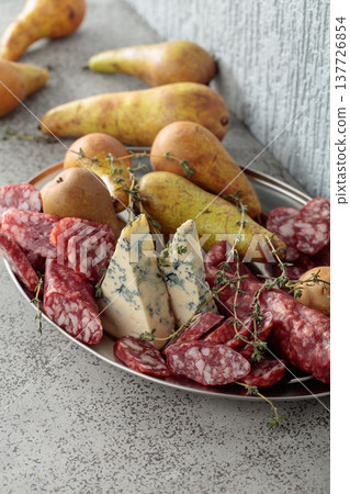 Blue cheese, dry-cured sausages, thyme and pears on a stone table. Blue cheese, dry-cured sausages, thyme and pears on a stone table. 137726854