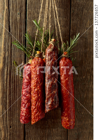 Smoked and dry cured sausages on a old wooden background. 137726857