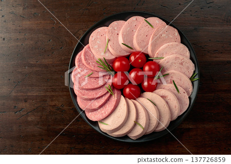Various boiled sausages with tomatoes and rosemary on a old wooden table. Various boiled sausages with tomatoes and rosemary on a old wooden table. 137726859