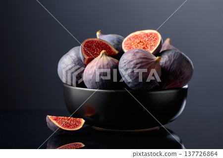 Ripe fig fruit in black dish on a black reflective background. Ripe fig fruit in black dish on a black reflective background. 137726864