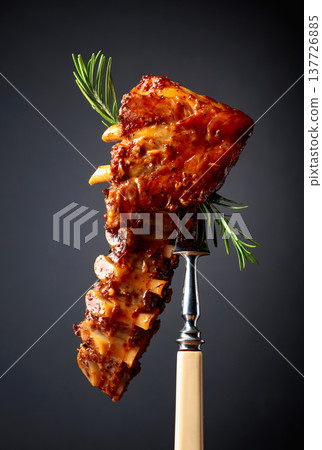 Grilled pork ribs with rosemary on a fork. 137726885