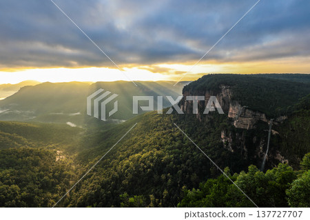 Golden sunrise light illuminating Grose Valley as seen from Govetts Leap Lookout in the Blue Mountains, New South Wales, Australia, with dramatic cliffs, layered ridges and morning atmosphere. 137727707