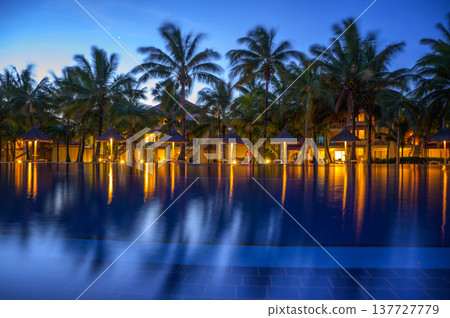 Resort swimming pool in Mauritius with palm trees and lights after sunset. Resort swimming pool in Mauritius with palm trees and lights after sunset. 137727779