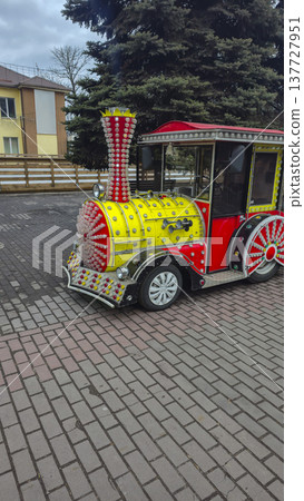 A bright children's train for rides in the city amusement park A bright children's train for rides in the city amusement park 137727951
