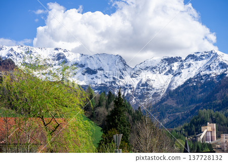 View of the snow-capped peaks of the Austrian Alps under white clouds in spring 137728132