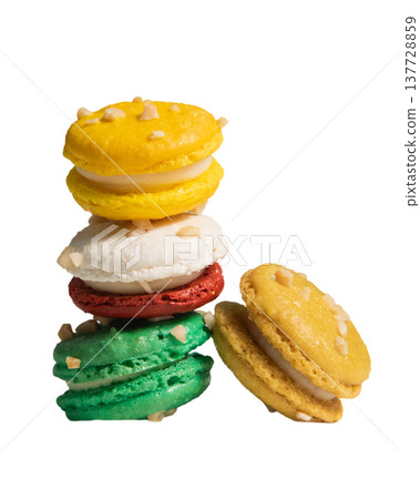 Colorful Macarons Stacked Artistically on a White Background, Featuring Yellow, Green, Red, and White Desserts with Nuts on Top, Perfect for Gourmet Treats 137728859