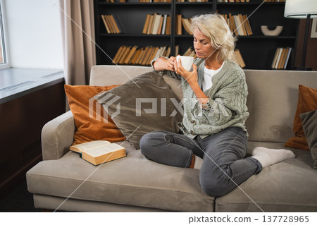 Good morning autumn winter fall vibe. Comfort relaxed senior old elderly woman drinking hot beverage tea coffee in sofa at home. Mature woman resting enjoy calm morning at home alone. Pension concept Good morning autumn winter fall vibe. Comfort relaxed senior old elderly woman drinking hot beverage tea coffee in sofa at home. Mature woman resting enjoy calm morning at home alone. Pension concept 137728965