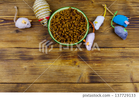 Set of mouses toys for cat and bowl with dry pet food on wooden background. Top view, copy space. Pet care concept Set of mouses toys for cat and bowl with dry pet food on wooden background. Top view, copy space. Pet care concept 137729133
