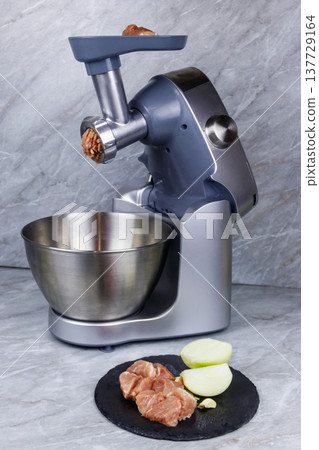 Electric eat grinder and fresh meat on kitchen table. Preparation of minced meat 137729164