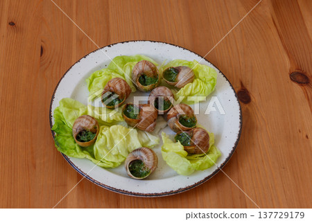Escargots de Bourgogne (snails) seasoned with butter, parsley, garlic on wooden table 137729179