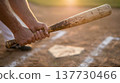 Close-up of batter hands gripping baseball bat over home plate at golden hour 137730466