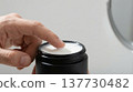 Macro of Man's Hand Dipping Into Matte Black Face Cream Jar 137730482
