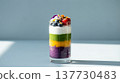 Vibrant Layered Parfait with Ube, Mango, Matcha and Coconut Cream on Blue-Gray Background 137730483