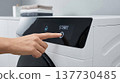 Finger Touching Digital Sensor on Modern White Washing Machine Display 137730485