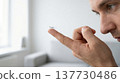 Close-up profile of man holding contact lens on fingertip 137730486