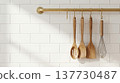 Wooden Kitchen Utensils Hanging on Brass Rail against White Subway Tile 137730487