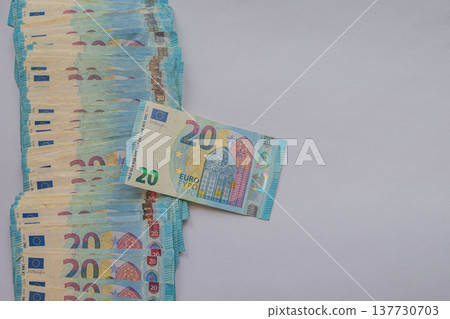 A vertical row of 20 Euro banknotes on a white background with one bill in focus. Minimalist financial layout featuring vibrant blue currency and large copy space A vertical row of 20 Euro banknotes on a white background with one bill in focus. Minimalist financial layout featuring vibrant blue currency and large copy space 137730703