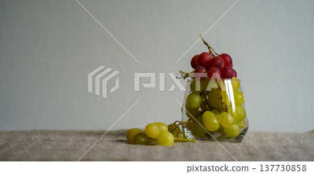 Bunches of ripe red and white grapes in a transparent glass Bunches of ripe red and white grapes in a transparent glass 137730858